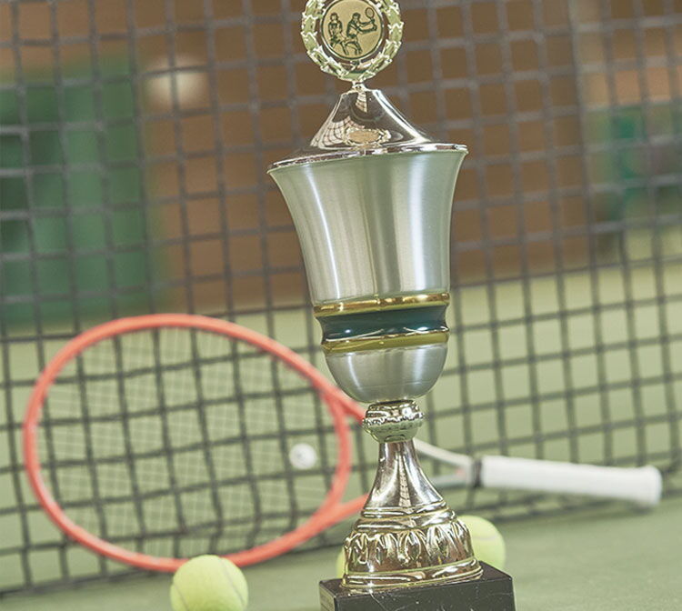 Detailaufnahme Tennispokal, Tennisschläger und Ball vor Netz