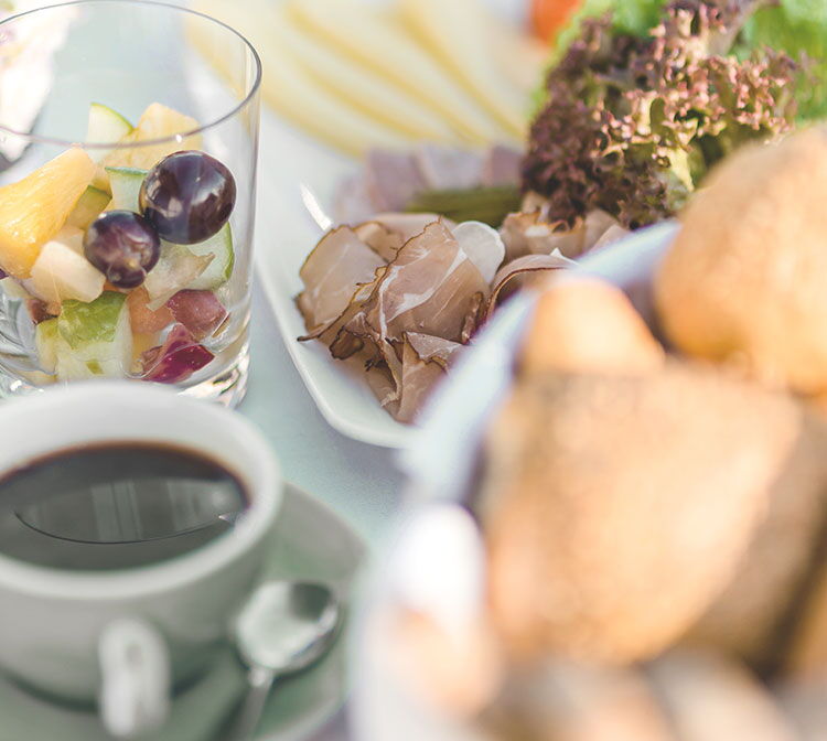 Nahaufnahme eines leckeren Frühstücks mit Obst, Kaffee, Brötchen und Wurst- und Käseplatte
