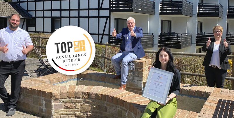 Hoteldirektor und Mitarbeiter des Sporthotel Grafenwald stehen vor dem Apartmenthaus und freuen sich über die Auszeichnung als Top Ausbildungsbetrieb