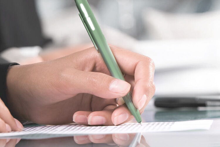 Hand schreibt mit grünem Kugelschreiber auf Papier während einer Tagung im Sporthotel Grafenwald