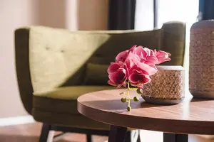 Sitzecke mit grünem Sessel und rundem Tisch im Hotelzimmer.