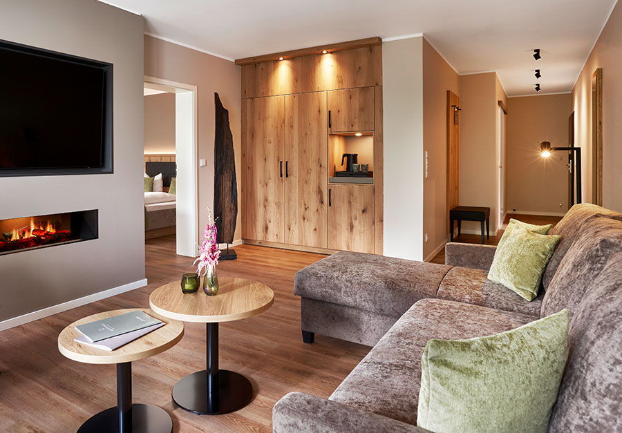 Innenaufnahme des neuen Zimmers mit Fernseher, Kamin und kuscheligem Sofa