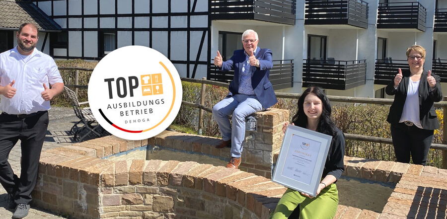 Hoteldirektor und Mitarbeiter des Sporthotel Grafenwald stehen vor dem Apartmenthaus und freuen sich über die Auszeichnung als Top Ausbildungsbetrieb