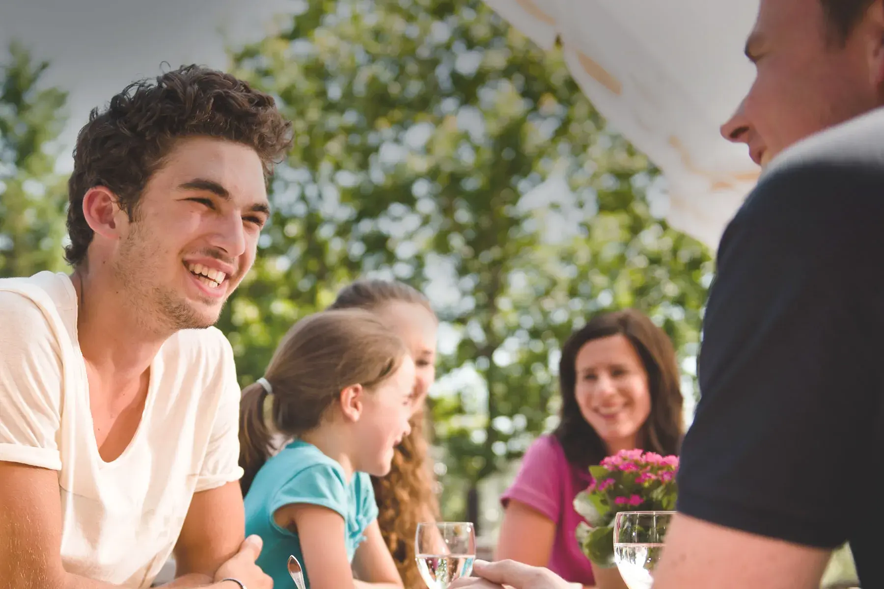 Familie sitzt auf der Sonnenterrasse des Sporthotel Grafenwald und unterhält sich angeregt Familie sitzt auf der Sonnenterrasse des Sporthotel Grafenwald und unterhält sich angeregt
