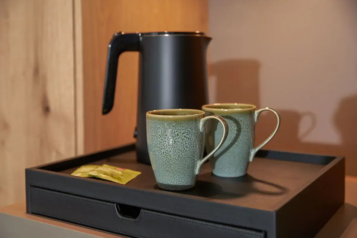 Ausstattungsdetail im Zimmer: zwei Tasen und ein Wasserkocher mit Teebäuteln auf einem schwarzen Tablett