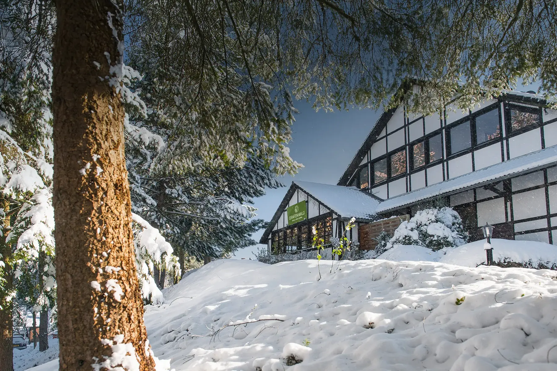 Haupthaus mit grünem Grafenwald Schild in winterlicher Schneelandschaft Haupthaus mit grünem Grafenwald Schild in winterlicher Schneelandschaft