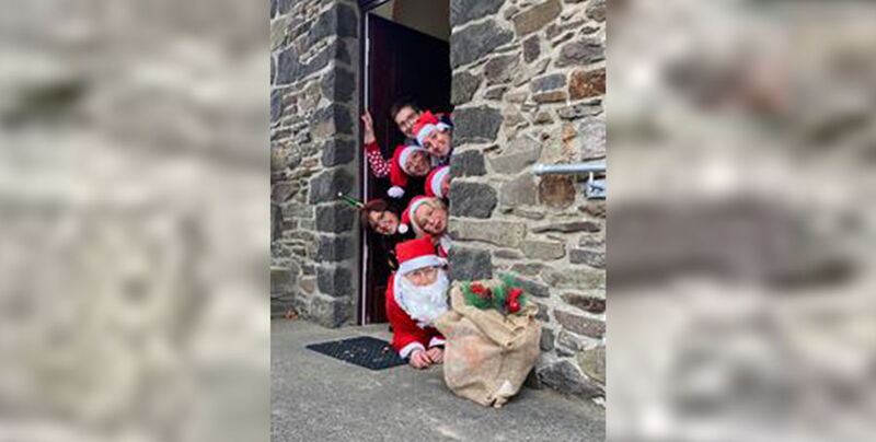 Mitarbeiter des Senionrentreffs sind als Nikoläuse verkleidet und schauen um die Ecke