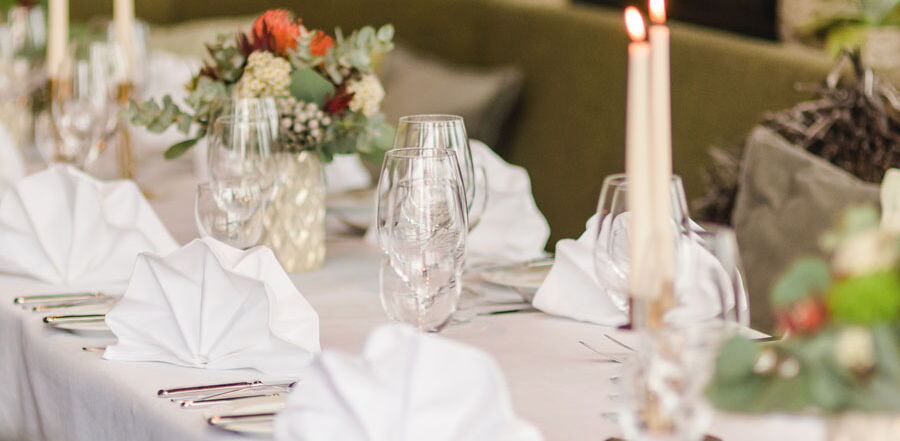 Detailaufnahme gedeckter Tisch mit Gläsern, Servietten, Blumen und Kerzen im Restaurant Grafenwald