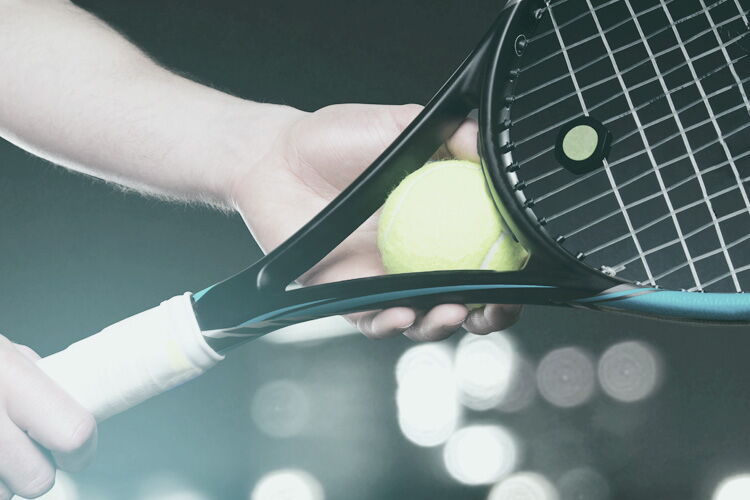 Hand mit Tennisschläger und Ball vor grünem Hintergrund